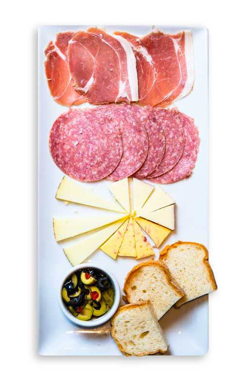A plate of cheeses, cured meats, olives, and ciabatta bread
